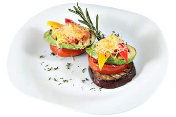 Tower of roasted vegetables on ceramic oval plate on white.