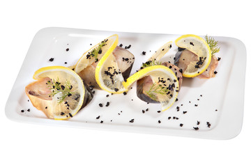 Sliced bonito cold smoked with lemon slices on rectangular plate