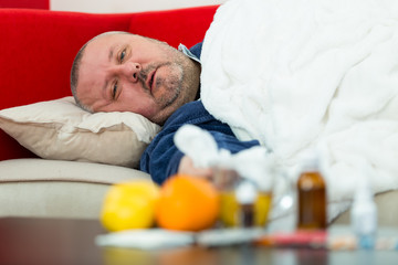 Sick man in bed with drugs and fruit on table