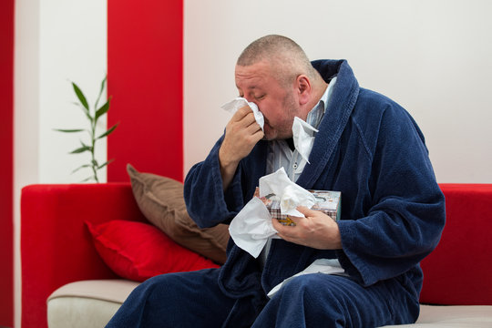 Man Having A Cold Holding Tissue With Box Full Of Tissues