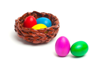Colored eggs on a white background. Wicker basket with eggs.