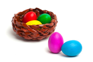 Fototapeta na wymiar Colored eggs on a white background. Wicker basket with eggs.