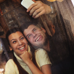 Young happy coupletaking selfie at cafe, view through a window