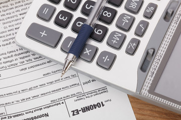 Calculator and pen on tax form Background