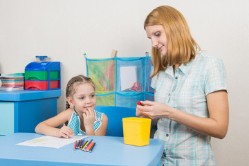 Five-year girl with interest looks like mom sharpens pencils