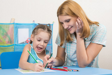 Five-year girl and young mother having fun drawing happy drawing with crayons