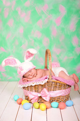Newborn baby girl in a rabbit costume has sweet dreams on the wicker basket. Easter Holiday