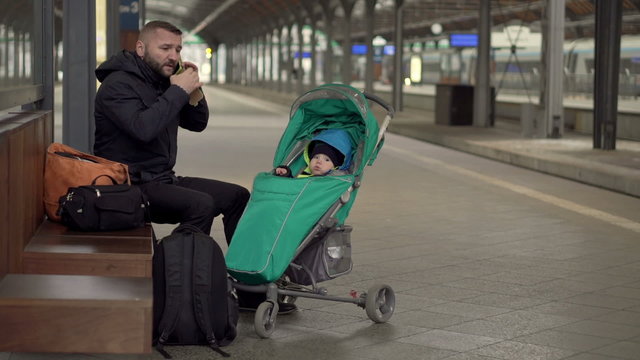 Upset Father with kid waiting on station , cellphone 
