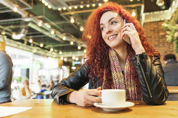 Young woman talking on the phone in coffee shop.
