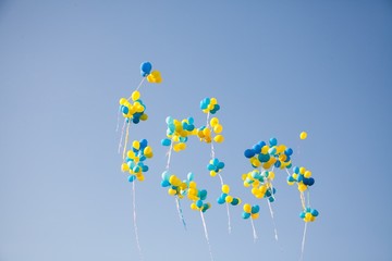 Bright colorful inflatable balloons up in air over blue sky background.