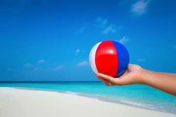 Fototapeta na wymiar female hand holding a ball at a beautiful beach with a turquoise