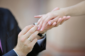 Obraz na płótnie Canvas groom's hand putting a wedding ring on the bride's finger