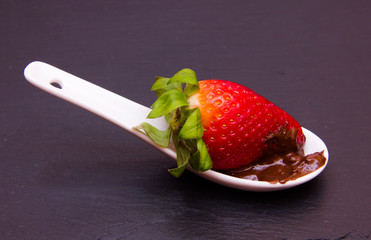 Teaspoon with strawberry and chocolate on top in slate
