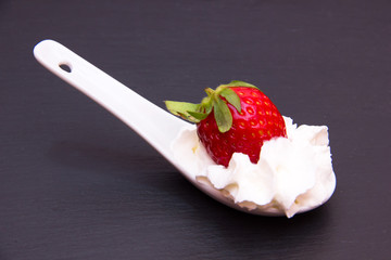 Teaspoon with strawberry and cream on top in slate