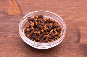 Cloves on glass bowl on wooden table