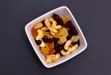 Dried fruits on a square bowl on slate top seen from above