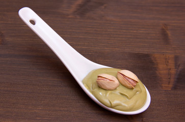 Pistachio cream on spoon on wooden table