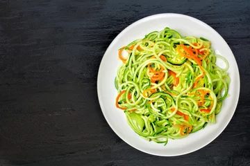 Photo sur Plexiglas Plats de repas Low carb zucchini noodle dish with carrots and lime on dark slate background, overhead view