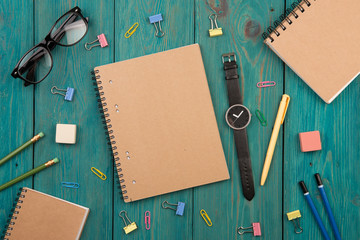 Workplace with notepad, glasses, watch and other office supply o