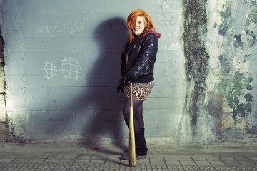 Smiling punk woman posing with a baseball bat.