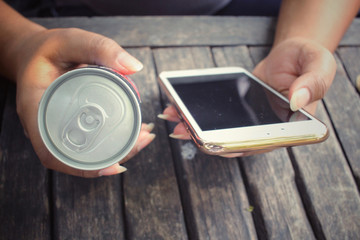 Woman using smart phone with aluminum can