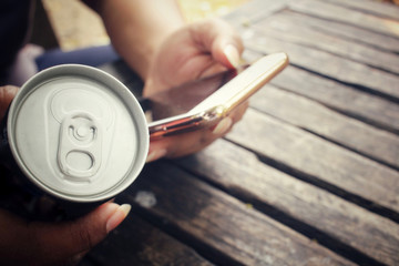 Woman using smart phone with aluminum can