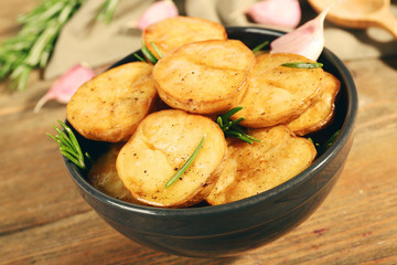 Delicious baked potato with rosemary in bowl on table close up