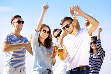 Young people with beer on the riverside