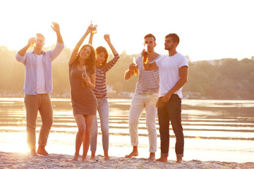 Obraz premium Young people with beer on the riverside