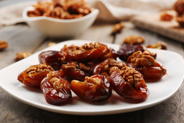 Walnut and date fruit in plate on wooden table, close-up