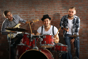 Musicians playing the drums on brick wall background