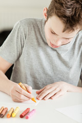 Obraz na płótnie Canvas Male Teenager Making Art on Paper Using Crayons