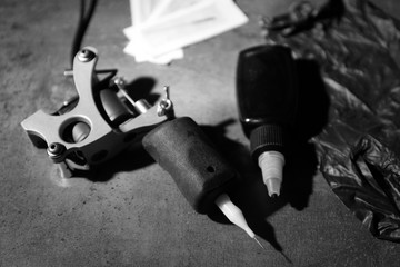 Tattoo machine and tattoo supplies on dark background