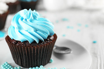 Delicious chocolate cupcake with blue cream on decorated wooden  table, close up