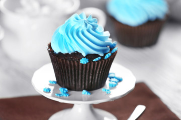 Delicious chocolate cupcake with blue cream on served table, close up