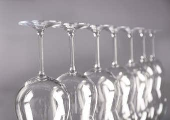 Wine glasses in a row upside down on light grey background