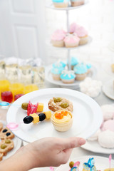 Woman holding plate with snacks and canape on buffet background