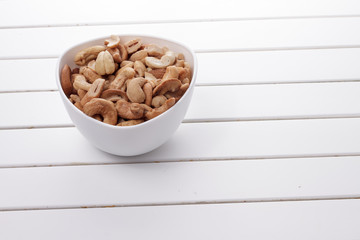 Pile of cashew nuts in a bowl on white wooden table