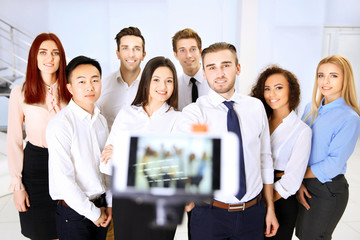 Young people making group photo with smart phone in office
