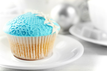 Tasty blue cupcake on plate with decorations, closeup