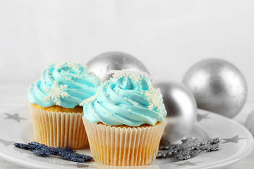 Two tasty blue cupcakes with decorations on light background