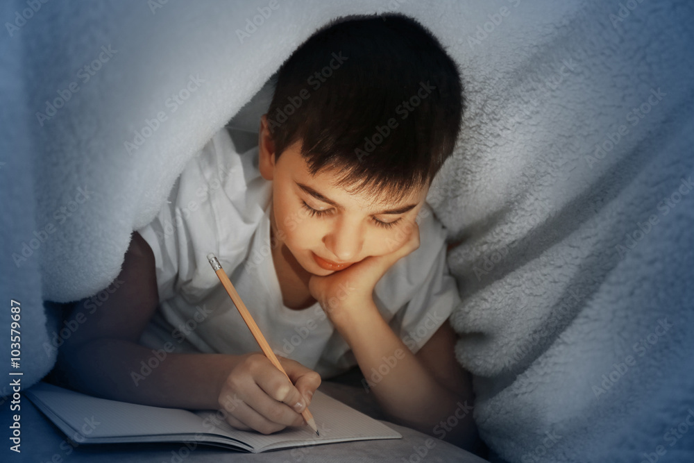 Wall mural little boy writing with pencil under the blanket