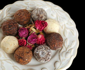 Assorted chocolate candies on white plate over black background