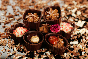 Assorted chocolate candies with flakes on black background