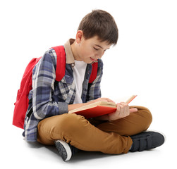 Cute little boy with red backpack reading a book, isolated on white