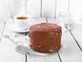 Chocolate cake with cup of tea and blade on a wooden table background
