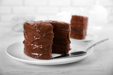 Chocolate cake on plate with a cut piece on unfocused background