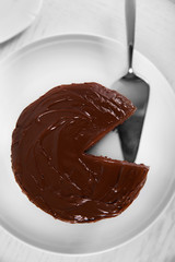 Chocolate cake on plate with a cut piece view from above