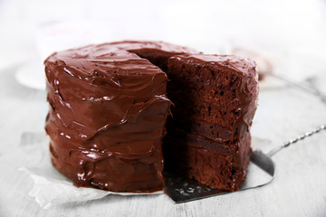 Chocolate cake with a cut piece on wooden table background, closeup