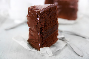 A piece of chocolate cake with forks on wooden table background, closeup